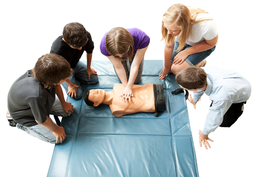 Photo of teenagers surrounding a CPR training manequin. One teen is practicing chest compressions